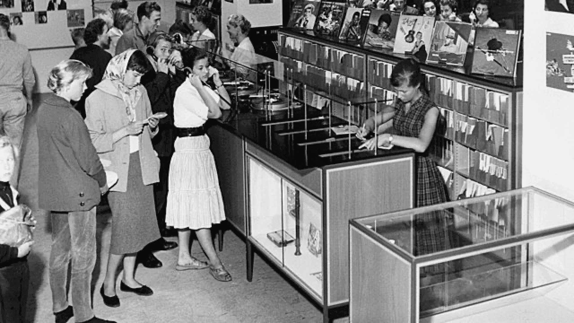 Black-and-white image of customers at a music store listening to vinyl records.